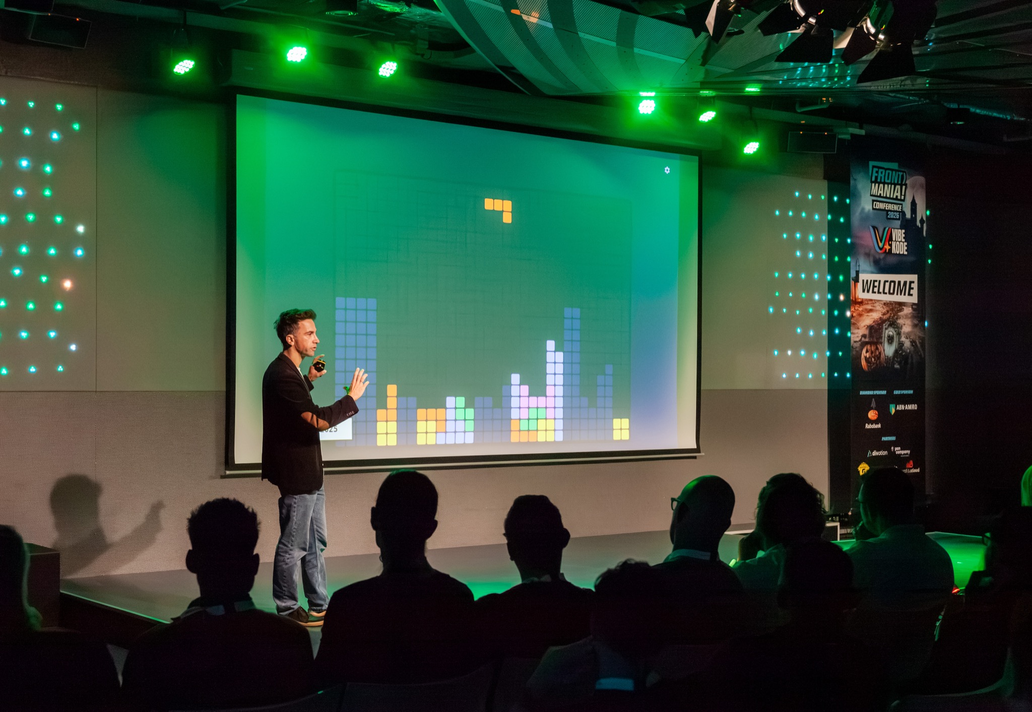 Speaking on stage at Frontmania 2026 with a colourful Tetris game projected behind me